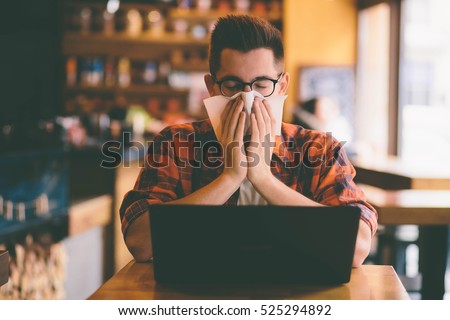 sick student blowing his nose into a tissue.