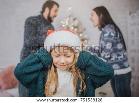 Sad, desperate little girl during parents quarrel. Clog the ears.. Family quarrel on the eve of Christmas
