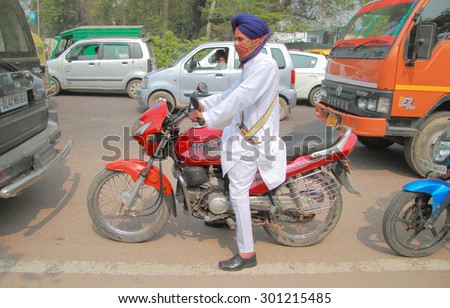 DELHI, INDIA - FEBRUARY 18, 2015: a man in traditional clothes on motorcycle stops in traffic jam in Delhi, India