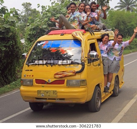 MEDAN, INDONESIA - APRIL 15, 2015: students are going to celebrate of finishing of school and moving to tourist place in the van - someone even on the roof of van