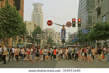 SHANGHAI, CHINA - JULY 1, 2015: people are crossing road by crosswalk in Shanghai, China
