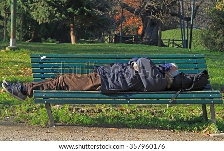 MILAN, ITALY - NOVEMBER 27, 2015: man is sleeping in park of Milan, Italy