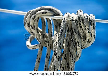A photo of a rope tied off to a boat stay, against the blue of the sea