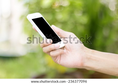 Hand holding smart phone with green background
