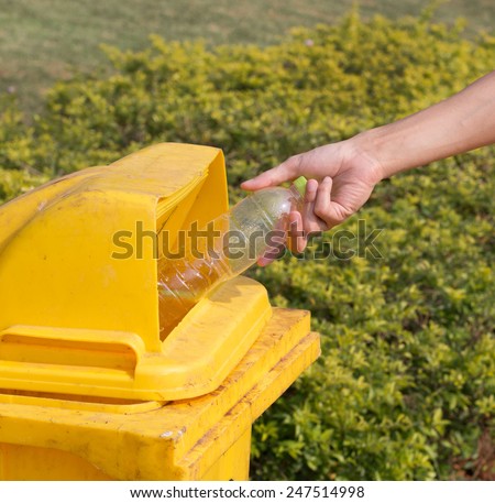Hand throwing empty bottle in the yellow bin.