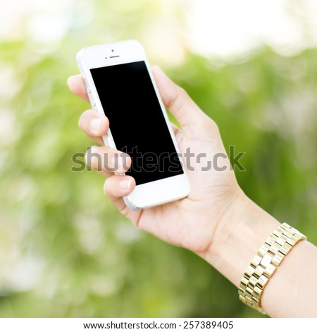 Hands using smart phone in green field