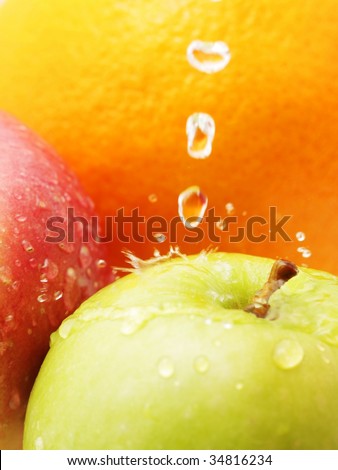 Abstract shot of apples and oranges with water droplets splashing on apple