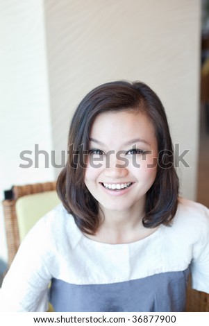 Beautiful young chinese girl dressed trendily laughing candidly in a cafe restaurant
