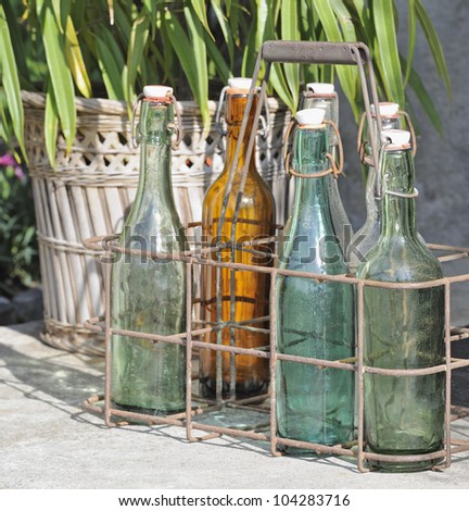 Closeup of old colored stopper bottles on doorstep in wire bottle holder