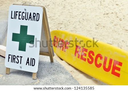 Lifeguard sign first aid and surf rescue surfboard on sandy beach