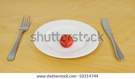 Decision dice used to choose meal. Empty white dinner plate, knife and fork on table