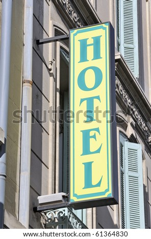 Closeup of hotel sign. Old european building with shutters. Sign is blue/green on yellow