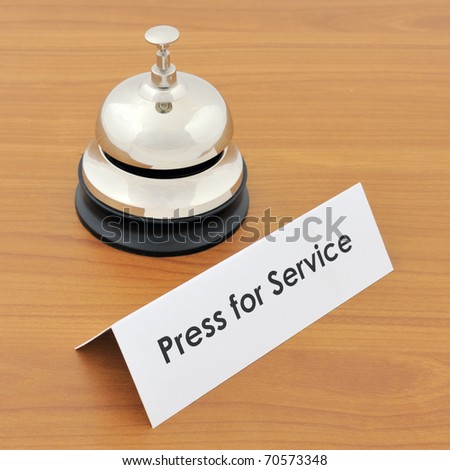 Closeup of service bell and sign on wooden desk