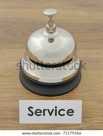 Closeup of service bell and sign on wooden oak desk