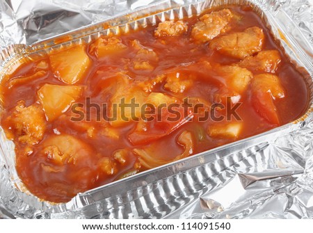 A takeaway foil bowl of Chinese sweet and sour chicken.