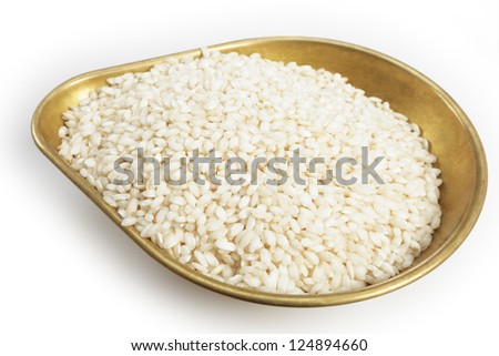 A pile of 460grams (one pound) of arborio Italian rice in the weighing pan from a set of scales, with a light shadow over white.
