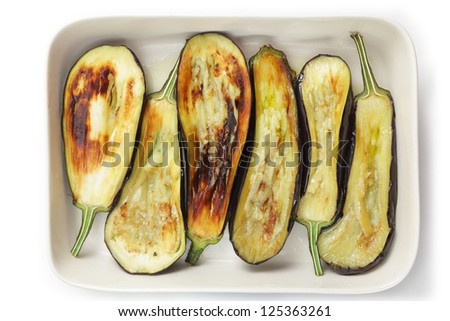Fried eggplant halves in a baking tray during the preparation of the Greek dish imam baildi or something similar.