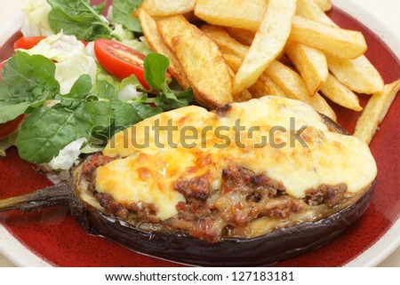 The Greek dish of aubergines stuffed with minced beef, onion and tomatoes, topped with bechamel sauce and cheese, served taverna-style with a salad of rocket, lettuce and tomato, and french fries