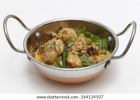 A kadai serving bowl of balti chicken pasanda curry, garnished with coriander leaves and a green chilli. This curry is made with yoghurt , cream and chopped coriander as well as the usual spices,
