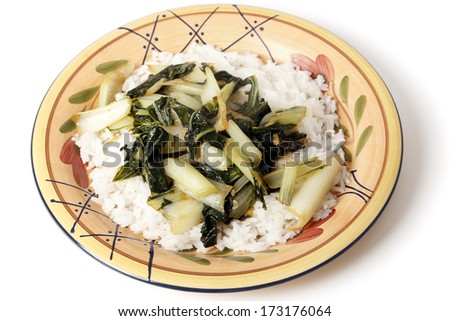 A plate with bok choi asian cabbage chopped and sauteed with sesame oil and soy sauce, served on a bed of white jasmine rice