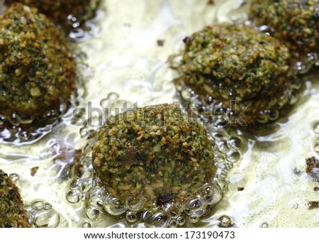 Homemade falafal mixture frying in oil. The balls comprise crushed soaked chickpeas, parsley and coriander leaves, coriander and cumin powder, chilli, paprika, salt and pepper.