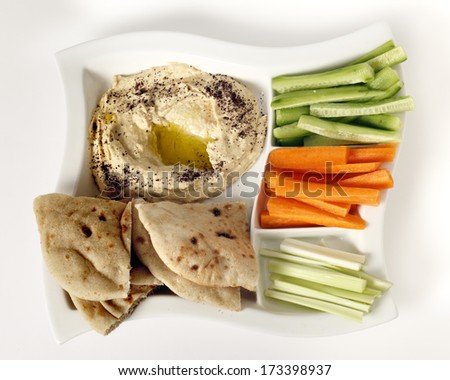 Top view of a dip tray with hummus, bread, carrot sticks, celery and cucumber.