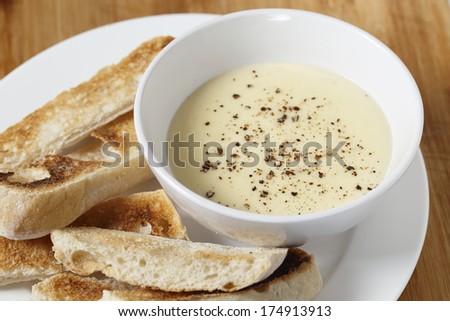 Cheese dip, made with soft cheese, milk, egg and butter in a bain marie, sprinkled with pepper and served with toasted ciabata crostini.