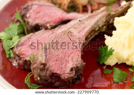 Lamb chops cut from a roast lamb rack and served with creamed garlic potato and onion relish