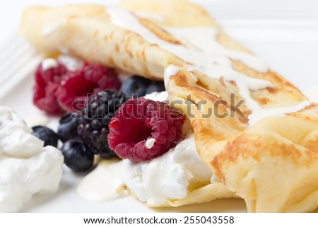 Crepe with yoghurt, raspberries, blackberries, blueberries, and a drizzling of cream