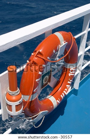 A lifebelt with and automatic signal light attached, on the rail of a large Greek ship.