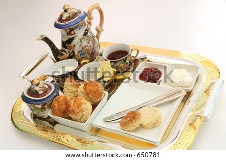 A gilt-edge tray with an English cream tea, featuring scones, cream, strawberry jam and tea, with a Chinese tea set.