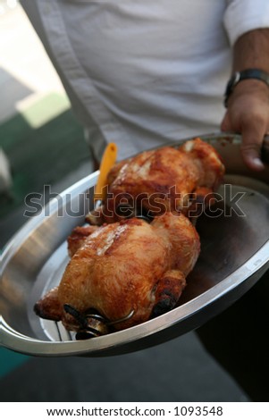 A restaurant worker displays chickens hot from the grill.