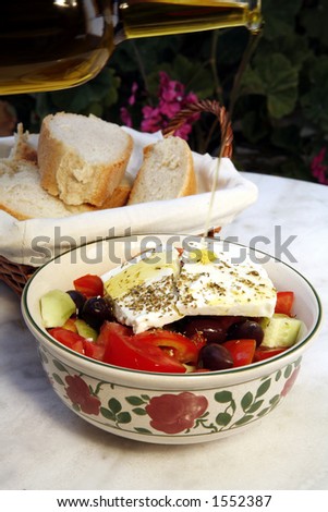 Greek country salad with feta, olive oil and bread on a traditional, marble-topped table.