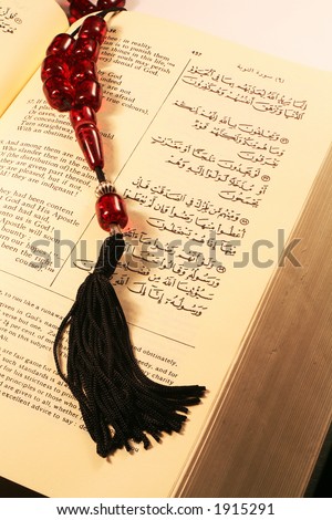 Page from the Holy Qu\'ran in Arabic and English, with prayer beads.
