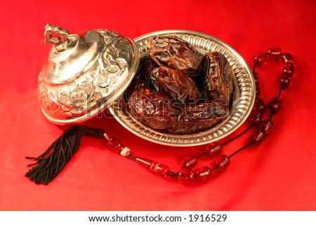 A silver bowl containing the finest dates which are traditionally eaten in Arabia for Iftar to break the Ramadan fast at sundown next to prayer beads. A silver bowl containing the finest dates which are traditionally eaten in Arabia for Iftar to break the Ramadan fast at sundown next to prayer beads.