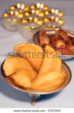 A traditional arab sweet filled sponge on an Iftar table for breaking the fast at the end of Ramadan. Dates and glass teacups are in the background. Shallow depth of field