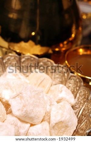 Turkish delight in a silver bowl on a Ramadan Iftar (fast-breaking) table, with a glass of green coffee and a coffee pot.