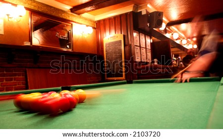 The pack scatters during a game of pool in an English pub. Deliberate motion blur.