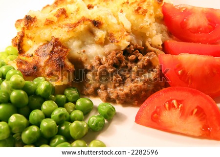 A meal of shepherd\'s pie - minced (ground) meat topped with parsley mashed potato an baked golden brown, served with peas and tomato