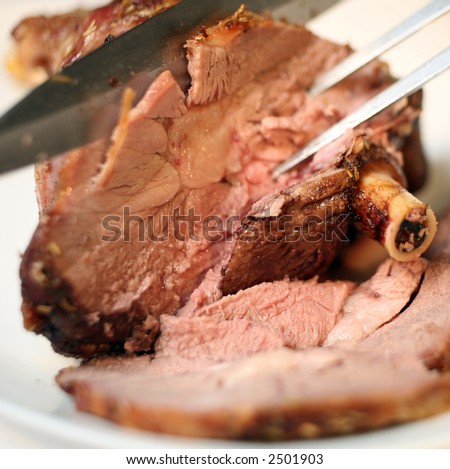 Carving slices of meat from a joint of lamb.
