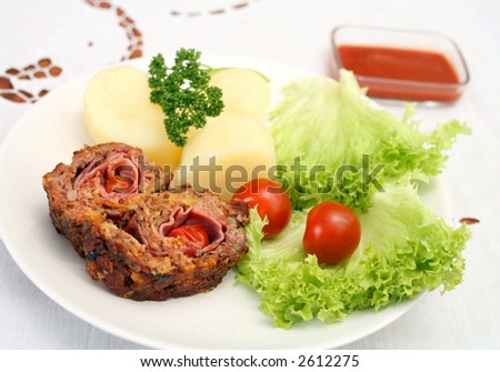 Beef roulade (rolled beef meatloaf) containing ham and cherry tomatoes, served with lettuce,boiled potato,cherry tomatoes and a tomato dip.
