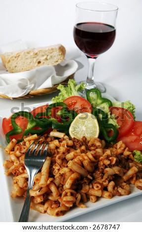 A plate of meat pasta and salad, served with Italian red wine and ciabatta bread