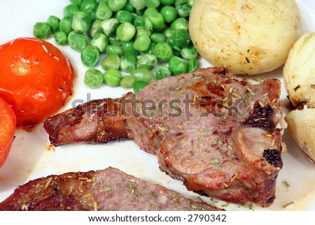 A chump chop grilled with rosemary and served with jacket potatoes, peas and grilled tomato