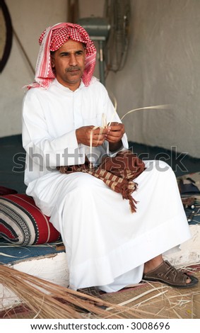 A Gulf Arab craftsman making small objects from dried reeds at the Doha Cultural festival. The focus is on the hands, face is slightly soft at full size.