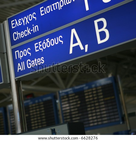A sign to the boarding gates in English and Greek at Eleftherios Venizelos International Airport, Athens. The flight departures information board is out of focus in the background