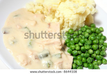 A plate of Chicken a la King, mashed potatoes and peas, close-up