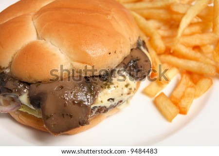 A mushroom and cheese beefburger, served with french fried potatoes. A typical fast-food restaurant meal