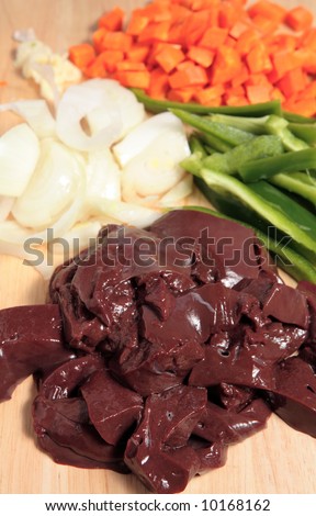 Chopped lamb\'s liver, onions, carrots and capsicums on a wooden board - ingredients for a delicious liver stew or stroganoff.