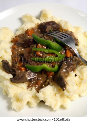 A meal of lamb\'s liver and onion stew (actually a stroganoff) with diced carrots served on a bed of creamed potato.