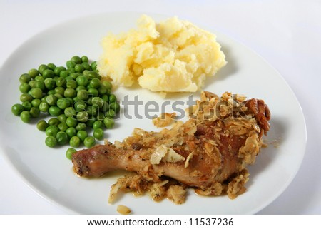 Chicken leg with an almond crust, a traditional French country recipe, served with mashed potatoes and peas